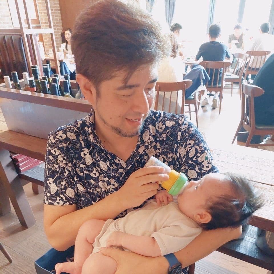 娘を抱き、ミルクを飲ませる三村ロンド